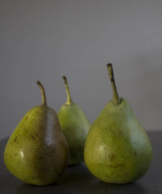 Taş masada yeşil armutlar. Yaz meyveleri fotoğrafı kapatır. Koyu gri arkaplan, kopyalama alanı. Gıda hala hayat. 