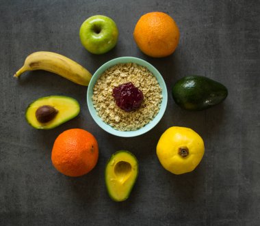 Sağlıklı kahvaltı malzemeleri üst manzara: mavi kâse, avokado ve yeşil elma yulaf ezmesi. Koyu gri arka planda fotokopi alanı olan bir hayat. Sağlıklı beslenme konsepti. Taze meyveler yakın.. 