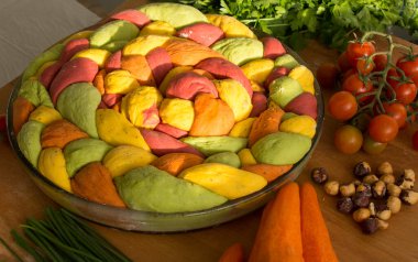 Ahşap masanın üzerinde pişirme formundaki renkli challah ekmeği. Taze sebzeler. Üst görünüm fotoğrafını içerir.
