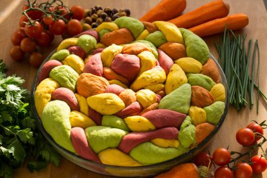 Ahşap masanın üzerinde pişirme formundaki renkli challah ekmeği. Taze sebzeler. Üst görünüm fotoğrafını içerir.