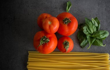 Masadaki makarna malzemeleri. Fotokopi alanı olan koyu gri arkaplanda taze sebzeler.. 