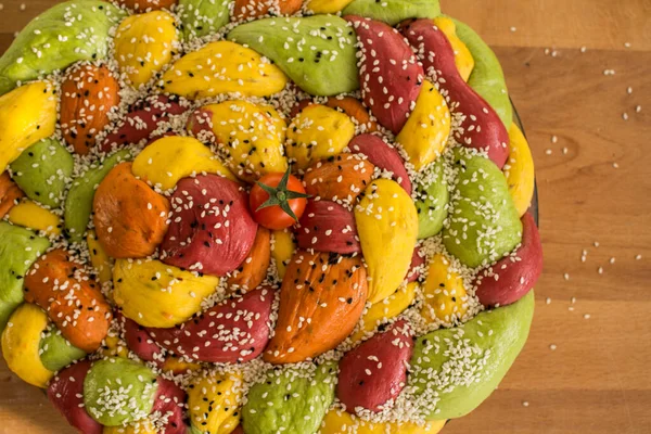 Ahşap masanın üzerinde pişirme formundaki renkli challah ekmeği. Taze sebzeler. Üst görünüm fotoğrafını içerir.