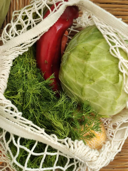 Seasonal vegetables in mesh bag. Red paprika pepper, cabbage, melon and dill in white cotton mash bag. Organic farm vegetables. Zero waste concept.