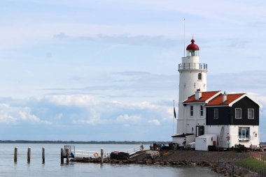 Klasik deniz kenarı fotoğrafı üzerinde beyaz deniz feneri. Idyllic manzara: kabarık bulutlu mavi gökyüzü, deniz dalgaları, suda gemiler.