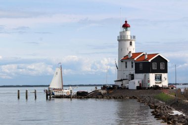 Klasik deniz kenarı fotoğrafı üzerinde beyaz deniz feneri. Idyllic manzara: kabarık bulutlu mavi gökyüzü, deniz dalgaları, suda gemiler