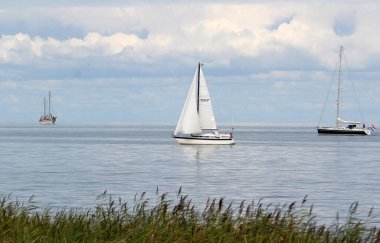 Klasik deniz kenarı fotoğrafı. Idyllic manzara: kabarık bulutlu mavi gökyüzü, deniz dalgaları, suda gemiler