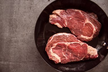 Çiğ et dokusu. Siyah ızgarada biftek. Kopyalama alanı olan gri arkaplan.