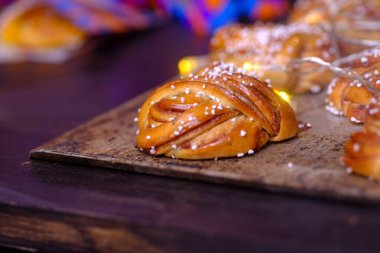 Pastanedeki ahşap masada lezzetli kenarları olan taze ve güzel bir çörek. İştah açıcı, sıcak, lezzetli, arka planda çıtır çıtır çörekler. Sıcak ışık ve güzel renkler, keskinlik ve kompozisyon..