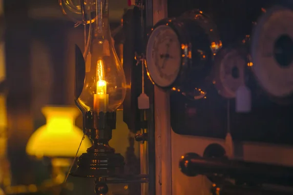 Eski bir lamba, çatı katı tarzı. Dikey cam plato ve ampul gibi sıcak bir mum. Bulanık koyu arka plan. İyi kompozisyon, büyük resim boyutu, doğal renkler ve gölgeler.