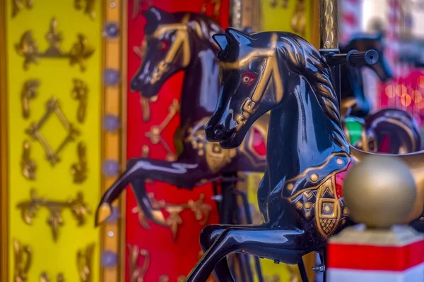 Çok renkli atlı karınca atları. Yapay ya da oyuncak atlar, dizginler, yeleler vs. boyanmış. Arka planda bazı boya direkleri, merkez sütun ve çeşitli dekorasyon elemanları yer almaktadır..