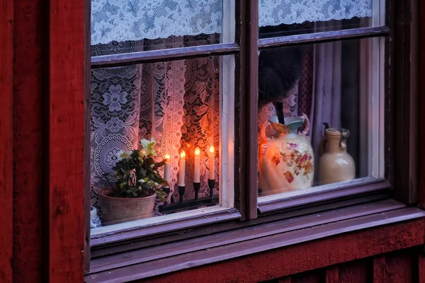Pencere dekorasyonu. Eski kırmızı-kahverengi ahşap pencere, bir saksıda çiçek, mumlar ve zarif seramik vazolarla güzelce dekore edilmiş. Hayatımızı daha aydınlık ve daha ilginç yapan basit küçük şeyler..