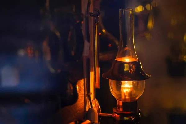 Eski bir ev lambası, çatı katı tarzı. Bronz yansıtıcısı ve sıcak Edison ampulü olan alışılmadık uzunlukta bir plato görebilirsiniz. Koyu arkaplan bulanık, yumuşak, ılık renkler. İyi kompozisyon, büyük resim boyutu, doğal renkler ve gölgeler.