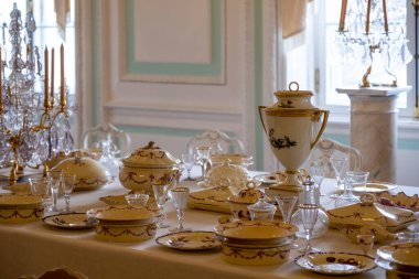 Bir düğün kutlaması ya da başka bir gala etkinliği için masa seti. Zarif bir porselen servisi, masa örtüsü üzerinde kristal bardaklar. Saray içi ve zengin dekorasyonu klasik tarzda. Doğal ışık.