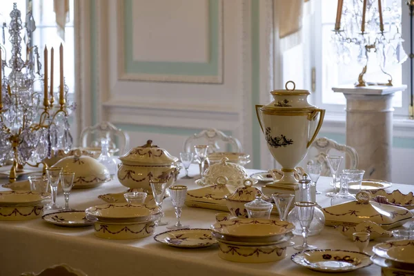 Bir düğün kutlaması ya da başka bir gala etkinliği için masa seti. Zarif bir porselen servisi, masa örtüsü üzerinde kristal bardaklar. Saray içi ve zengin dekorasyonu klasik tarzda. Doğal ışık.