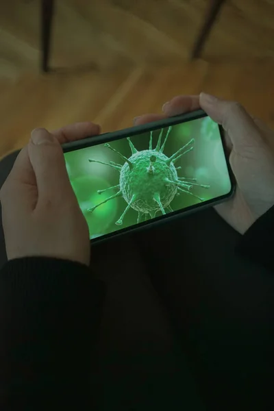 Girl holding mobile with coronavirus sign on the screen. Green corona sign on a mobile phone screen and a girl holding it. Coronavirus effects in daily life.  Coronavirus is in our hands in cellphone.