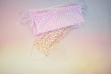 Beyaz arka planda küçük pembe çiçek desenli kumaş maske. El yapımı maske. Sabah güneşi. Kadınlar için kapalı koruyucu maske.