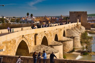 Mavi gökyüzü altında yürüyen insanlarla Cordoba 'nın Roma köprüsü, Endülüs, İspanya.