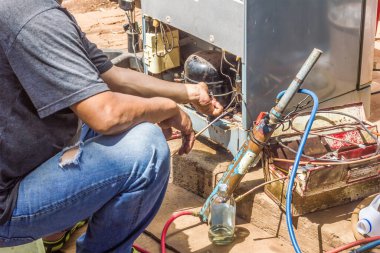 Bakım atölyesinde vakumla tamir edilen teknisyen buzdolabı