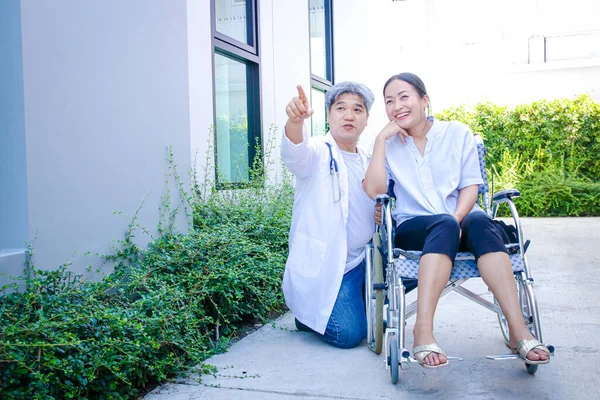 Elderly doctors treating female patients sitting on a wheelchair Along with suggesting basic self-care methods. Concept of rehabilitation for strong patients in the hospital