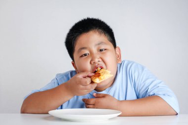 Şişko çocuk çok kilo almış, pizza yiyor.