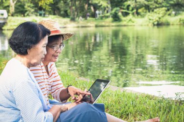 Parkta sosyal medyayı görmek için tablet oynayan iki yaşlı kadın. Mutlu emeklilik hayatı. Kıdemli topluluk kavramları. Boşluğu kopyala
