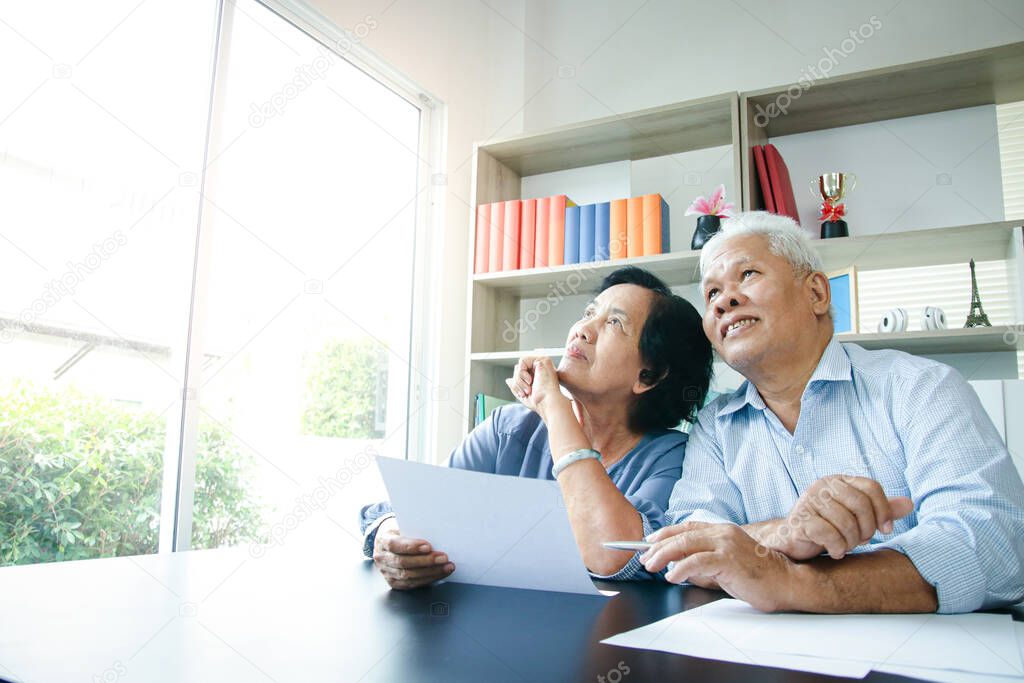 Elderly Asian couple sitting and documenting household income and expenses To be able to make plans for a happy and stable life. Retirement concept, social security, saving money. copy space