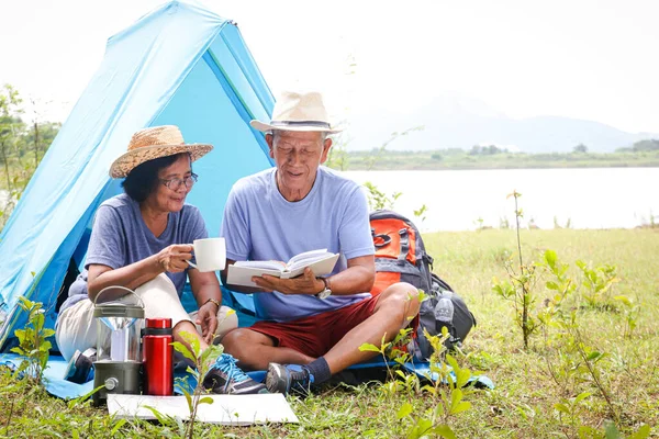 Two elderly lovers Camping in the forest Sitting and watching the paper map to study the hiking trails. The senior relaxation concept