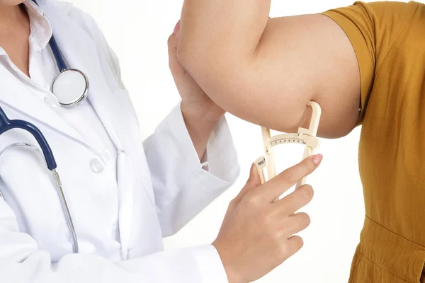 Kadın doktorlar şişman Caliper 'ı şişman kadınların kollarındaki yağı ölçmek için kullanırlar, kilo verme planlarında onlara yardım ederler. Beyaz arka plan. Sağlıklı yaşam kavramı