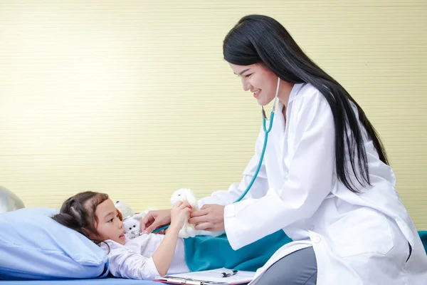 亚洲女医生用听诊器检查一个躺在病床上的小女孩的心跳 儿童保育的概念 — 图库照片