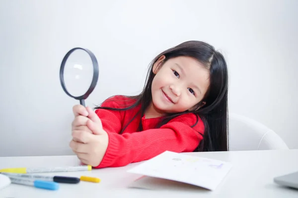 可爱的亚洲女孩拿着放大镜在课桌上 教育发展的概念 — 图库照片