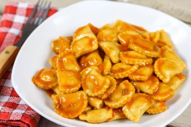 Ahşap bir masada domates soslu ravioli tabağı