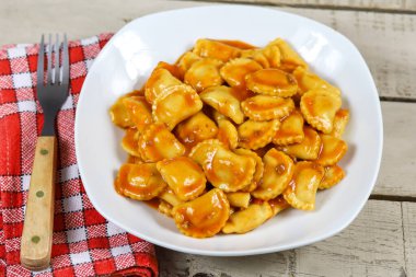 Ahşap bir masada domates soslu ravioli tabağı