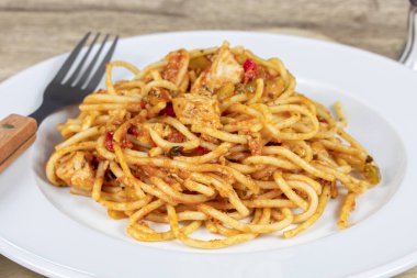 Tavuk ve domates soslu bir tabak spagetti.