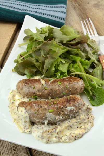 andouillette with a sauce and salad on a plate