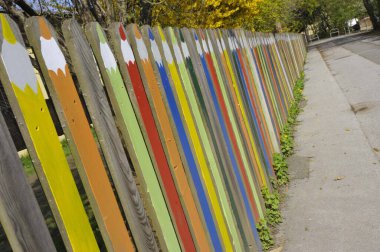 Çitin üzerinde renkli boya kalemleriyle boyanmış ahşap bir çit.