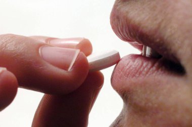 Hap alan genç bir adam, elinde haplar ağzında gezer.