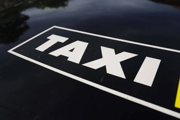 black and white Taxi sign on the hood of a car