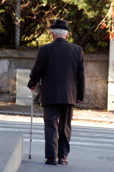 Old man with walking stick is walking on the streets
