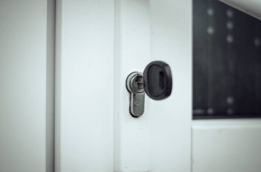 Anahtar, beyaz ön kapının kapı kilidinde. Yeni bir ev alıyorum.