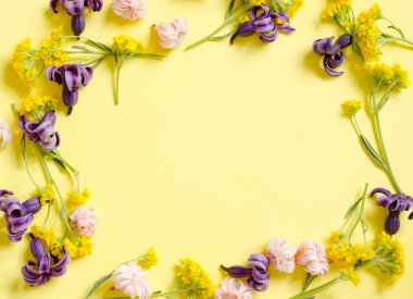 Sarı arka planda yakın plan çiçek çerçevesi. Mesajın için çiçekli bir arka plan. Pastel renkler.