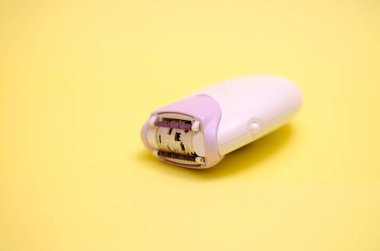 Sarı arka planda beyaz bir epilatör. Saç çıkarma konsepti