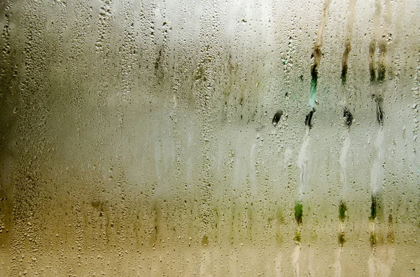 Indoor wet window on which droplets of water slide