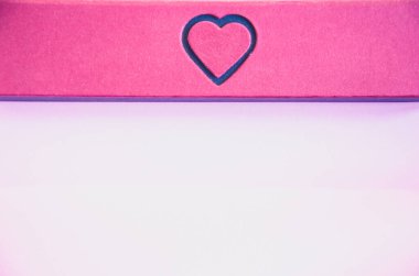 Pembe arka planda kalbi olan bir hediye kutusu..