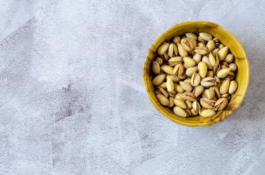 Gri arka planda fıstık kabuklu kahverengi kâse. Sağlıklı yeme kavramı