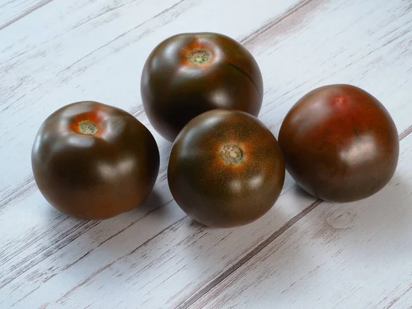 Τέσσερις Μαύρες Ντομάτες Κούματο Ανοιχτό Ξύλινο Φόντο — Φωτογραφία Αρχείου