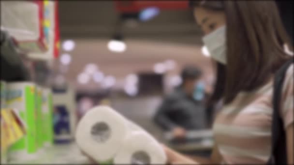 若いアジアの女性がマスク中にトイレの組織を選択しながら Covid 19危機の間に食料品店で紙を転がします 供給に在庫 コロナウイルス世界的なパンデミック ウイルス拡散防止4K Blurショット — ストック動画