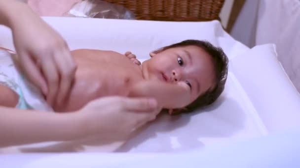 4Kアジアの保湿剤家庭でのシャワー後の小さな赤ちゃんの女の子のための摩擦体 居心地の良い 赤ちゃんはテーブルの上に横たわっ 蛍光灯 昼時間 純粋な 世話をする 子育て — ストック動画