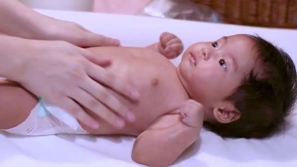 4Kアジアの保湿剤小さな赤ちゃんの女の子のための摩擦体自宅でシャワーした後 胸アームバック 赤ちゃんはテーブルの上に横たわっ 蛍光灯 昼時間 純粋な 世話をし 子育て — ストック動画