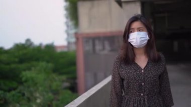 Beyaz koruyucu tıbbi maske takan Asyalı genç bir kadın. Dünya hastalıklı salgın yaşam tarzı, sağlık hizmeti Corona virüsü covid-19, gün batımı altın saati, karantina hayatı, yeni normal kadın maskesi tek başına yürüyor.