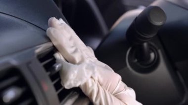Beyaz eldivenli el spreyleme ve cam yüzeyi silme, arabanın ön camını silme, dezenfektan bezi, Covid-19 Corona virüsü, araba bakımı, anti bakteri, hijyen yaşam tarzı, sabah ışığı.